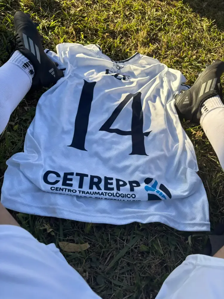Camiseta de fútbol número 14 sobre el césped entre botines negros